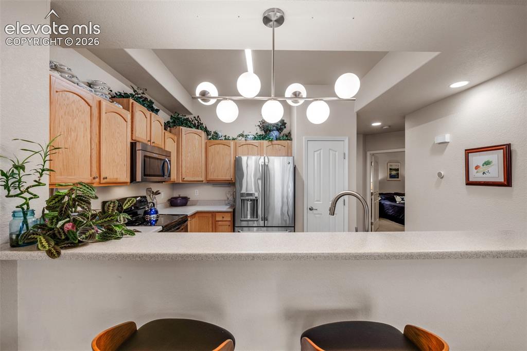 Image 10 of 32: Kitchen featuring wood cabinetry, stainless steel appliances, a bar-height 
