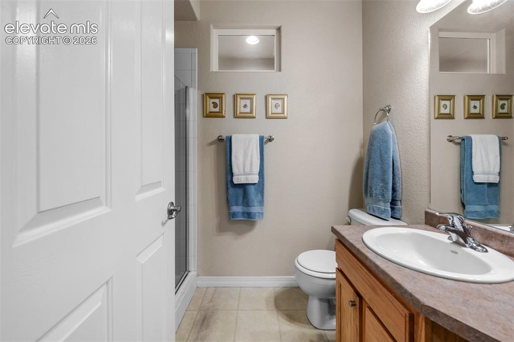 Image 12 of 32: Bathroom with a wood-finish vanity, integrated sink, and an enclosed shower