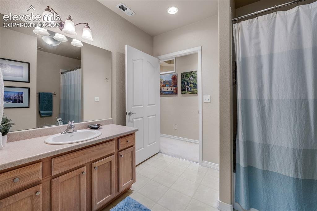 Image 20 of 32: Bathroom featuring a vanity with wood-finish cabinetry, a single basin sink