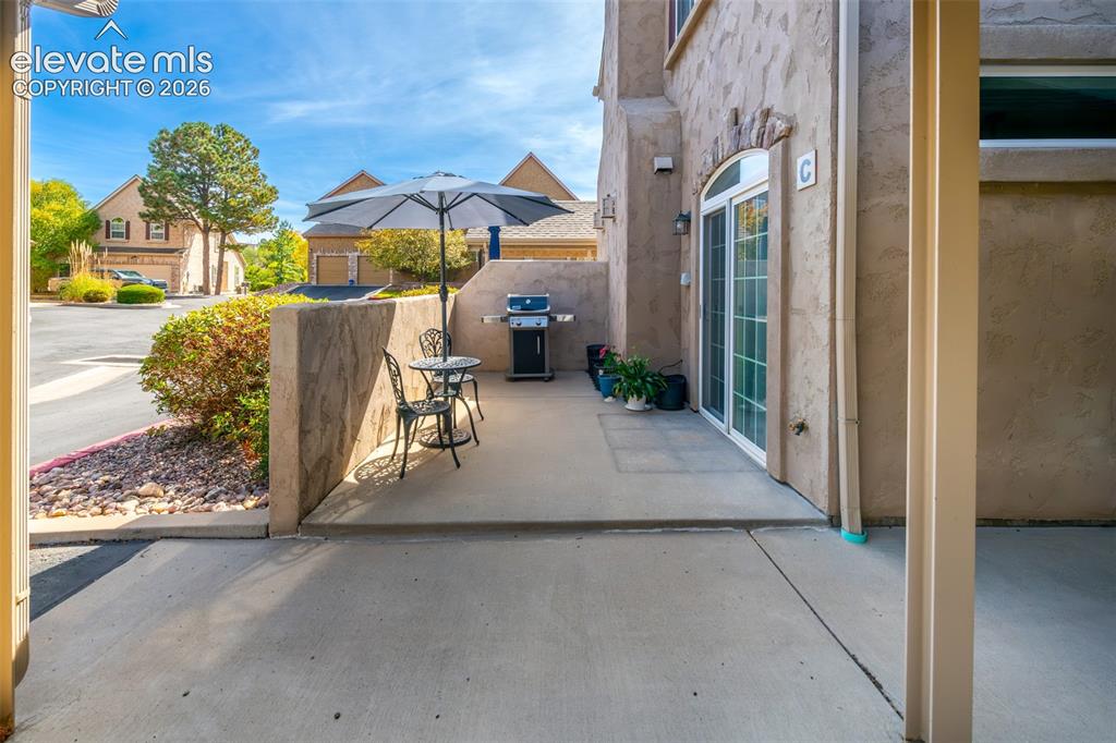 Image 22 of 32: Concrete patio with an arched glass sliding door, stone accent wall, and st