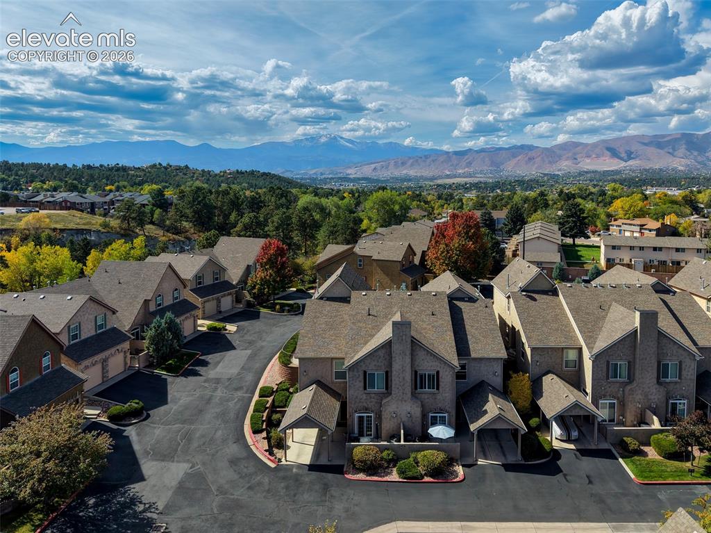 Image 27 of 32: Mountain backdrop, brick facades, attached garages, mature landscaping, pav