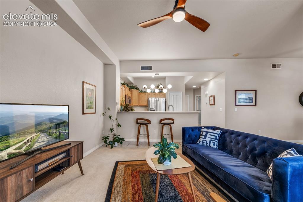 Image 3 of 32: Open-concept living area featuring a wood-finish media console, neutral car