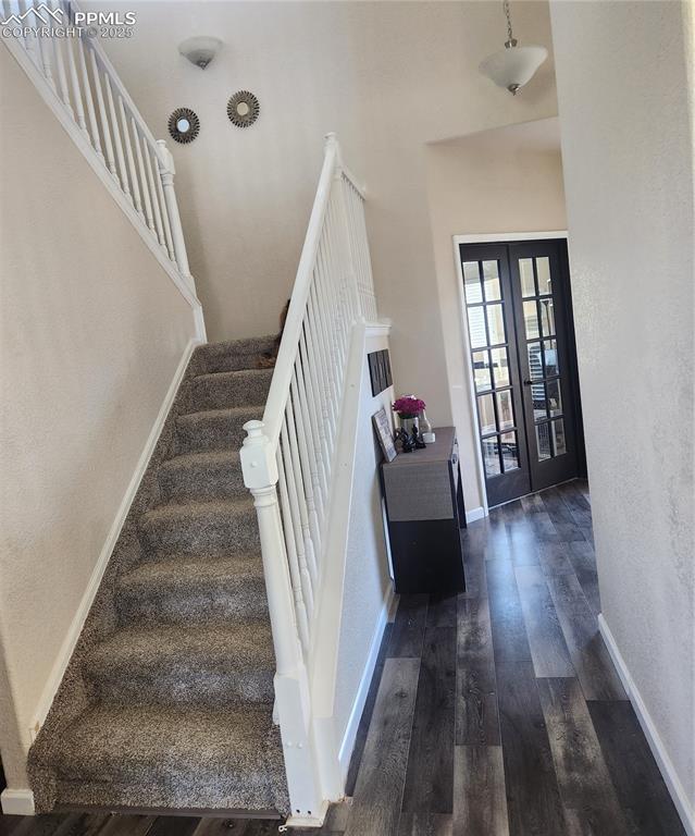 Image 15 of 45: Staircase featuring a textured wall, wood finished floors, french doors, an
