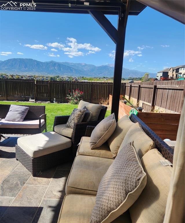Image 27 of 45: Fenced backyard with a mountain view, a patio area, and outdoor lounge area