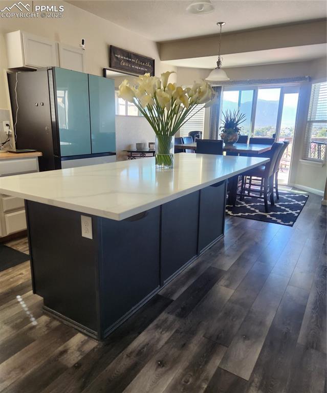 Image 29 of 45: Kitchen featuring fridge, decorative light fixtures, dark wood finished flo