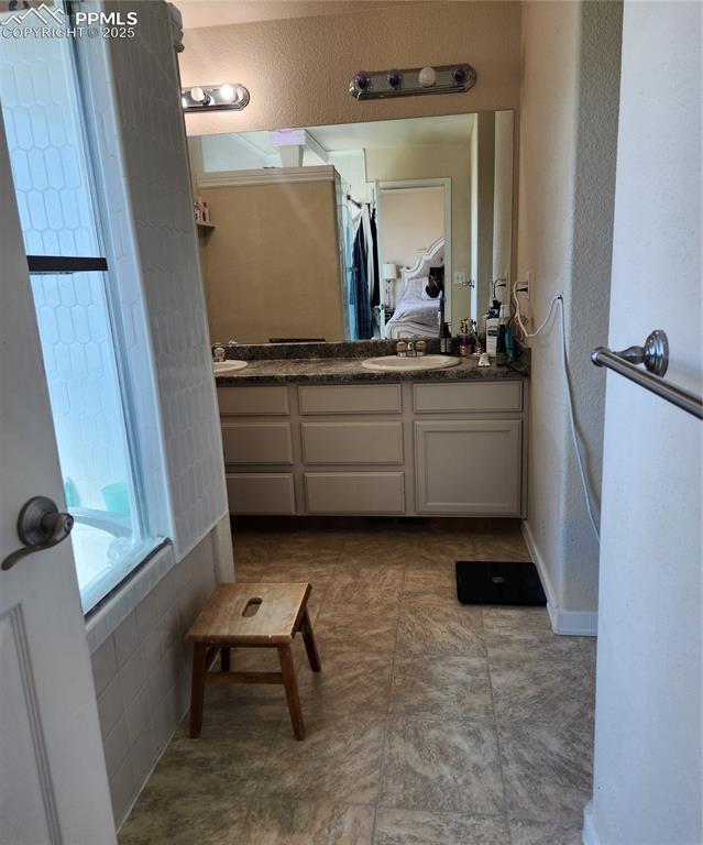 Image 30 of 45: Full bath with ensuite bath, double vanity, bath tub, a textured wall, and