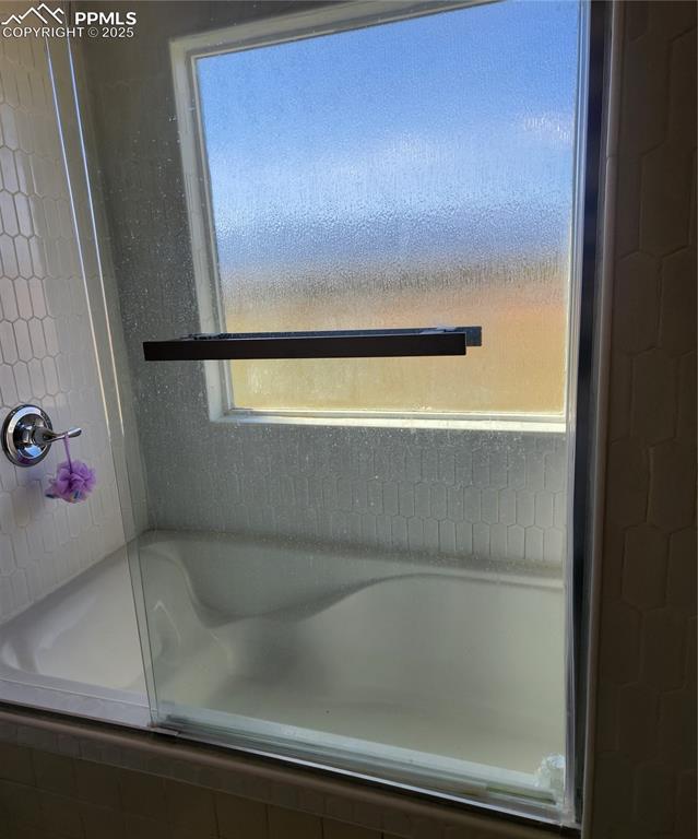 Image 33 of 45: Bathroom with shower / bath tub combination with glass door