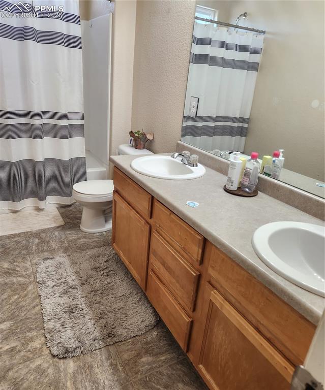 Image 34 of 45: Upper common Bathroom featuring double vanity, shower / tub combo, and a te