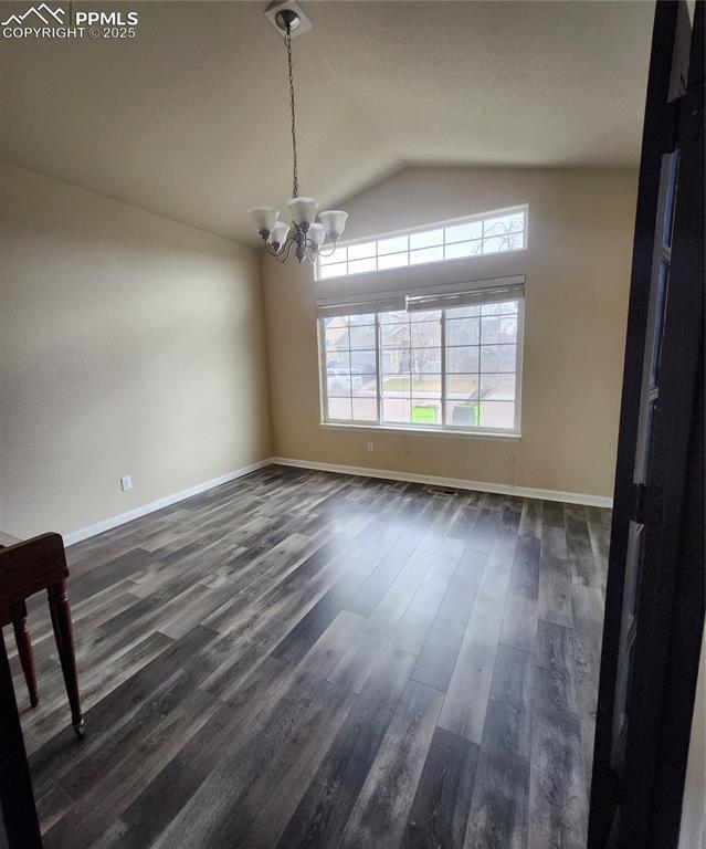 Image 41 of 45: Unfurnished dining area with a chandelier, vaulted ceiling, and dark wood-s