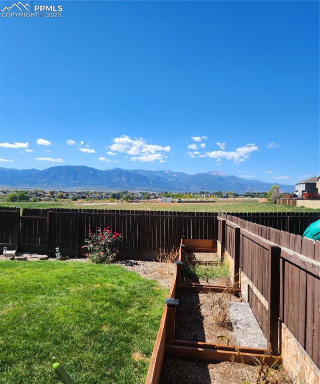 Image 7 of 45: Fenced backyard with flower box featuring a mountain view and a vegetable g