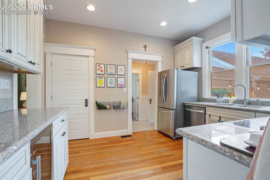 Image 12 of 37: Kitchen featuring light wood finished floors, beverage cooler, light stone
