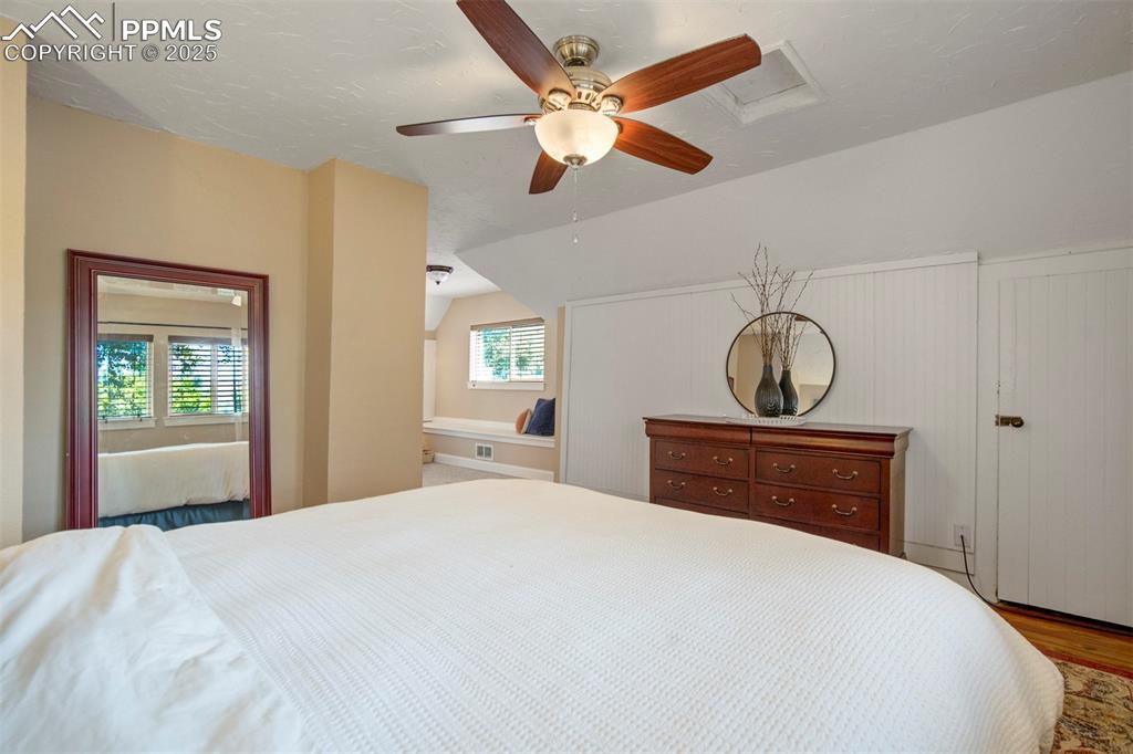 Image 22 of 37: Bedroom with attic access, vaulted ceiling, wood finished floors, a ceiling
