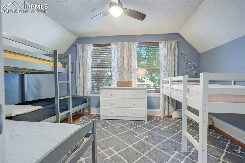 Image 24 of 37: Bedroom with lofted ceiling, a ceiling fan, dark wood-type flooring, and a