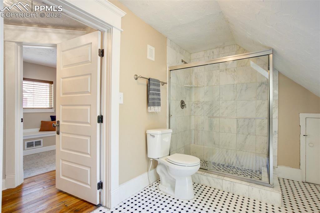 Image 28 of 37: Full bath featuring a stall shower, a textured ceiling, lofted ceiling, and