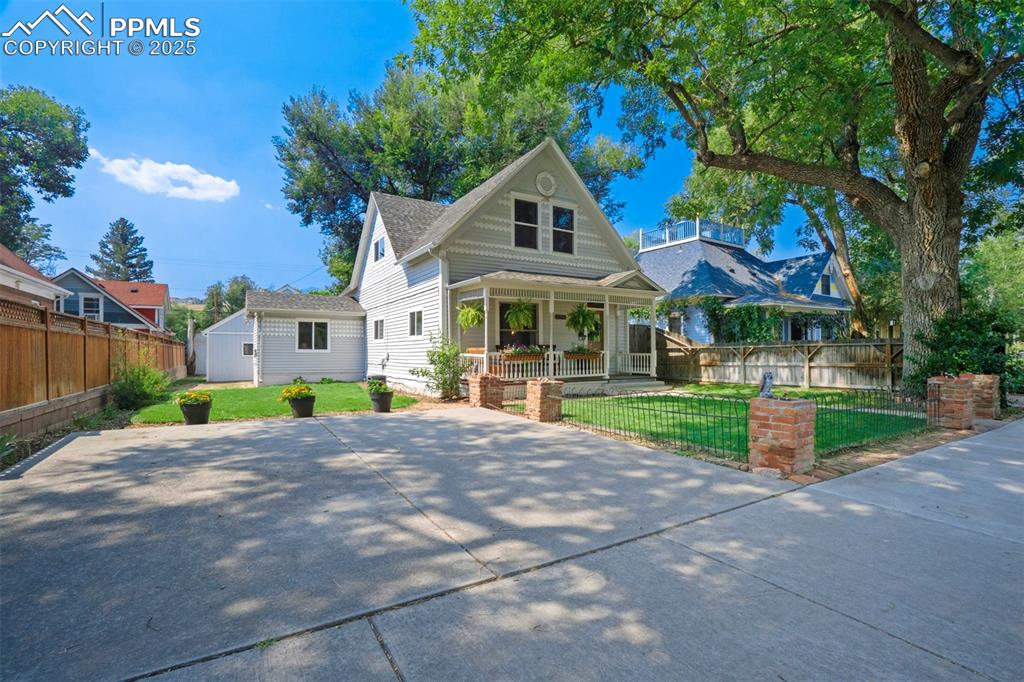 Image 35 of 37: View of front of home with covered porch, a fenced front yard, and an outdo