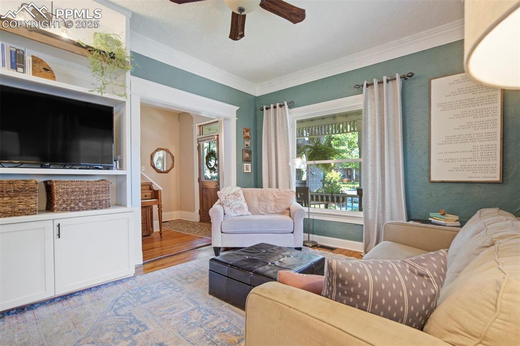 Image 7 of 37: Living area featuring wood finished floors, crown molding, and a ceiling fa