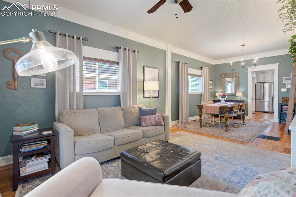 Image 8 of 37: Living room with wood finished floors, ornamental molding, a ceiling fan, a