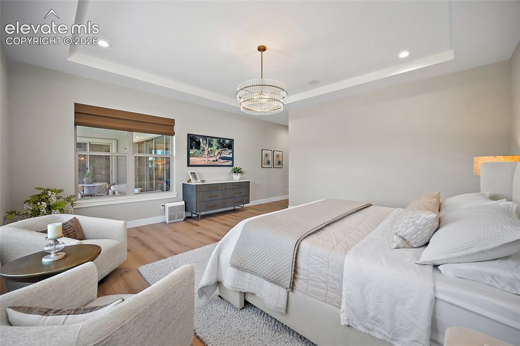 Image 26 of 45: Tray ceiling with recessed lighting and a decorative chandelier
