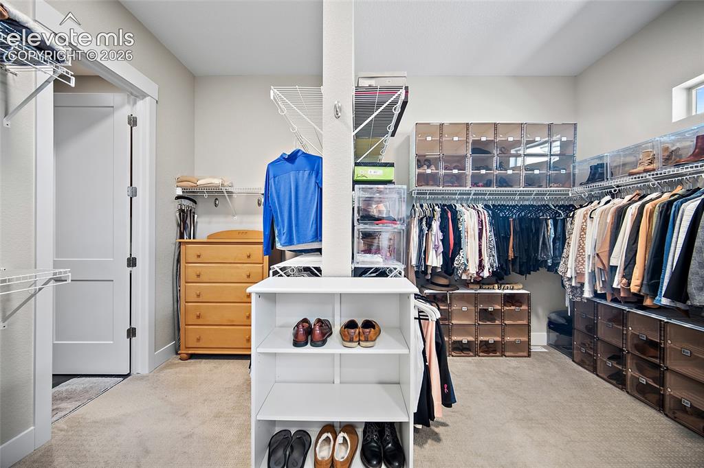 Image 30 of 45: generous primary closet with direct access to custom laundry room