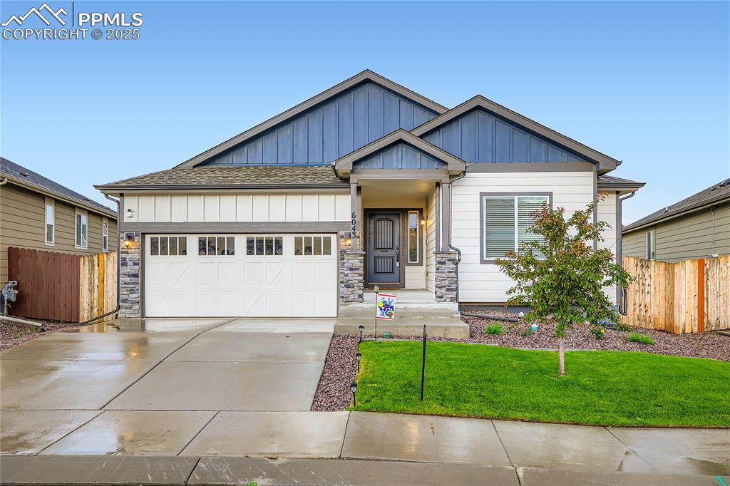 Caption: Craftsman-style house with board and batten siding, driveway, an attached garage, and roof with shin