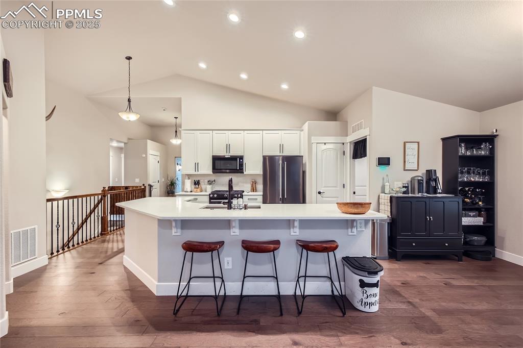 Image 10 of 37: Kitchen featuring stainless steel appliances, lofted ceiling, dark wood-sty