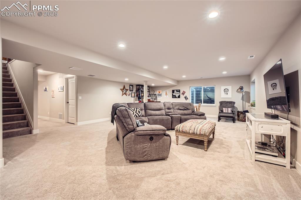 Image 19 of 37: Carpeted living room with stairway and recessed lighting