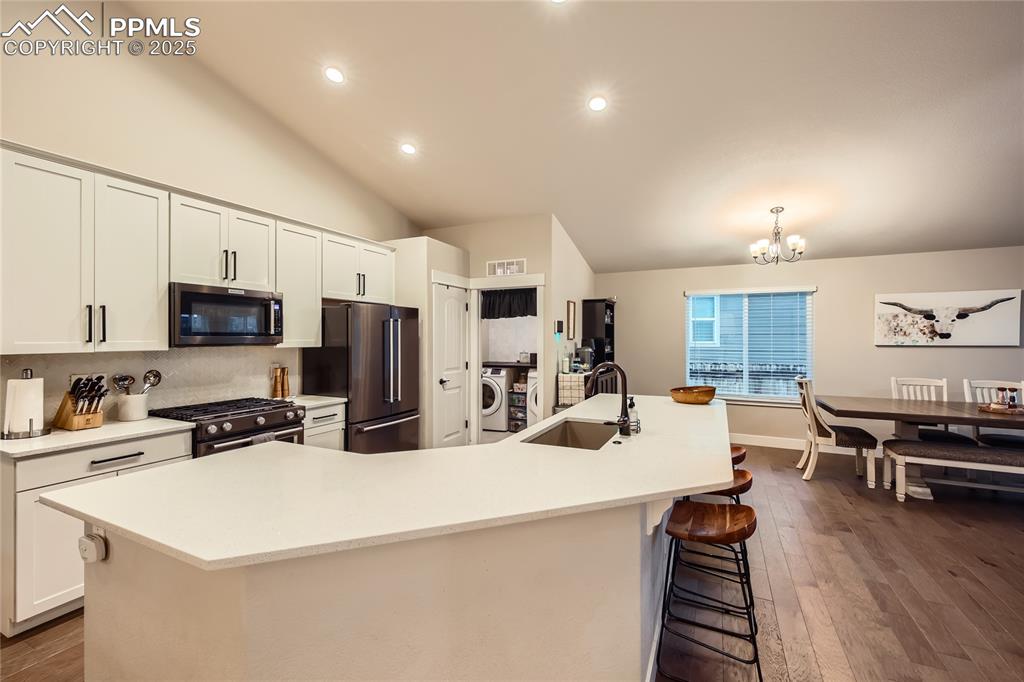 Image 7 of 37: Kitchen with stainless steel appliances, washer / clothes dryer, dark wood-