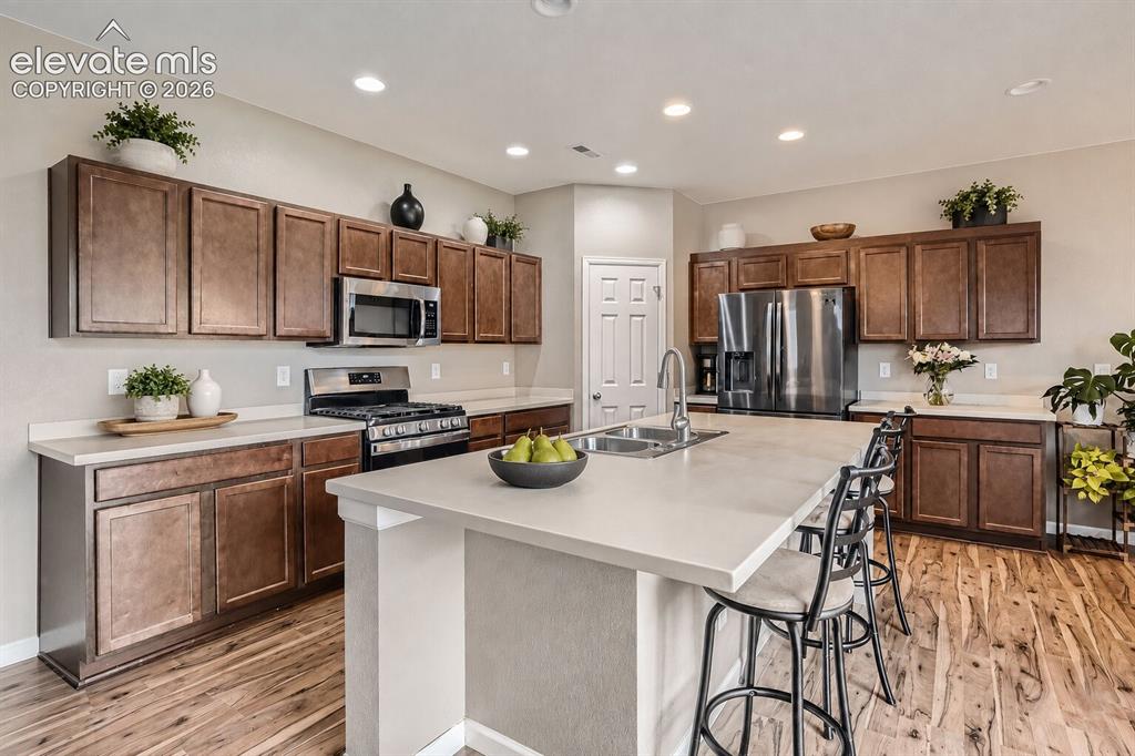 Image 4 of 35: Kitchen featuring stained wood cabinetry, stone-surface countertops, center