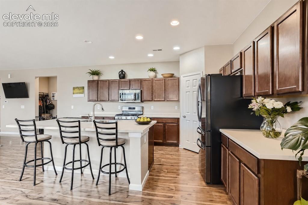 Image 5 of 35: Kitchen featuring dark wood-finish cabinetry, solid-surface countertops, a