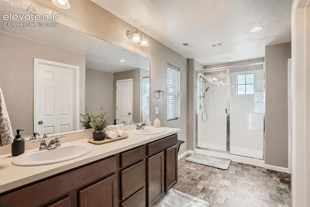 Image 7 of 35: Dual-sink vanity with a solid-surface countertop, full-width wall mirror, d