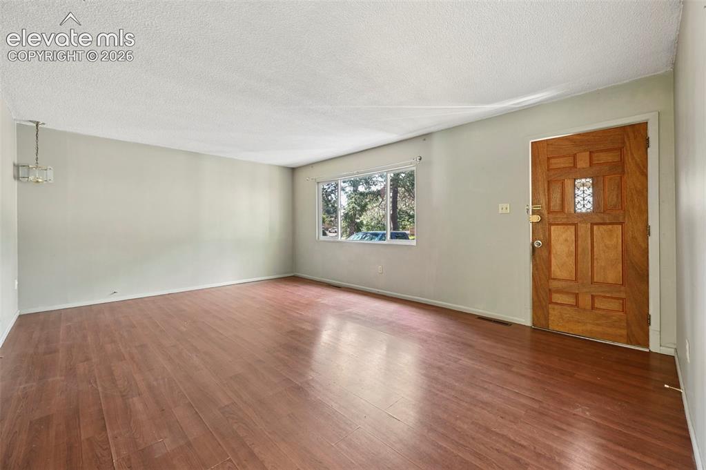 Image 13 of 32: Open living space featuring wood-finish flooring and a front entry door wit
