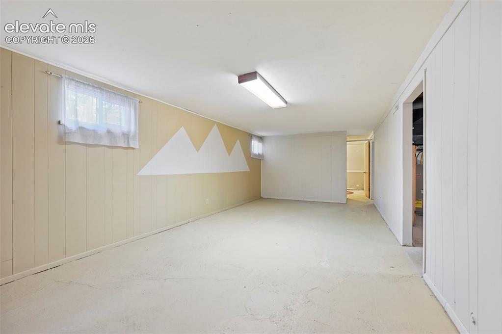 Image 15 of 32: Finished basement room featuring painted concrete flooring and paneled wall