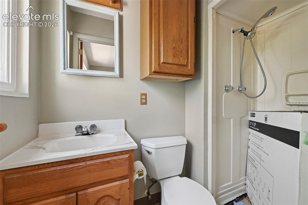 Image 20 of 32: Compact bathroom featuring a corner vanity with integrated sink, wood-finis