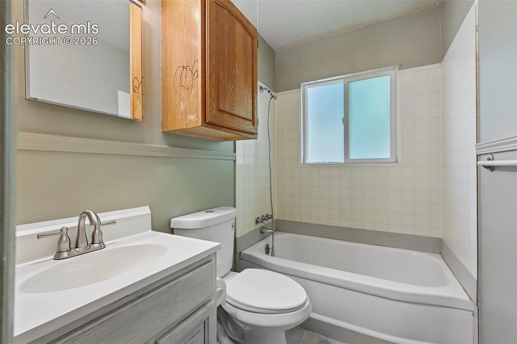 Image 21 of 32: Bathroom featuring a white bathtub, frosted window, white tiled surround, w