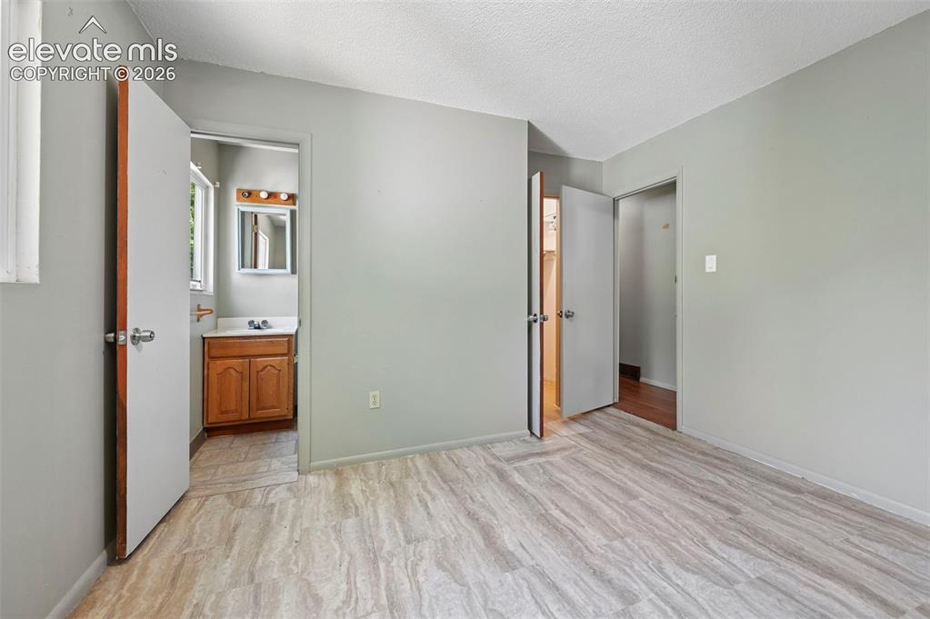 Image 22 of 32: Light gray walls and wood-finish flooring define this interior space