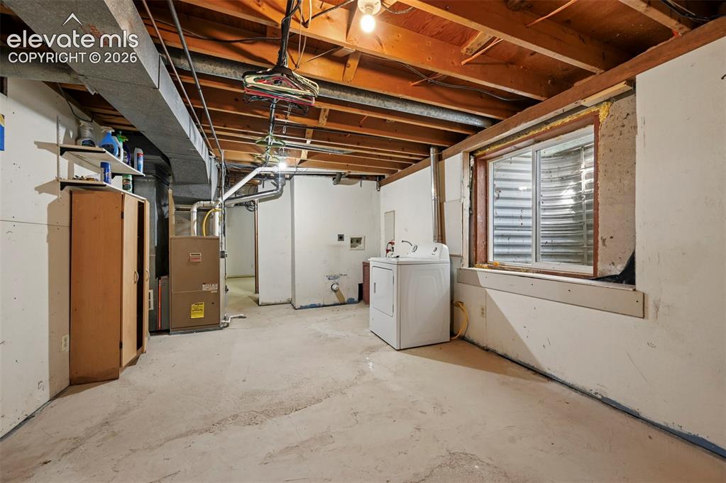 Image 24 of 32: Open basement area featuring concrete flooring, exposed ceiling joists, and