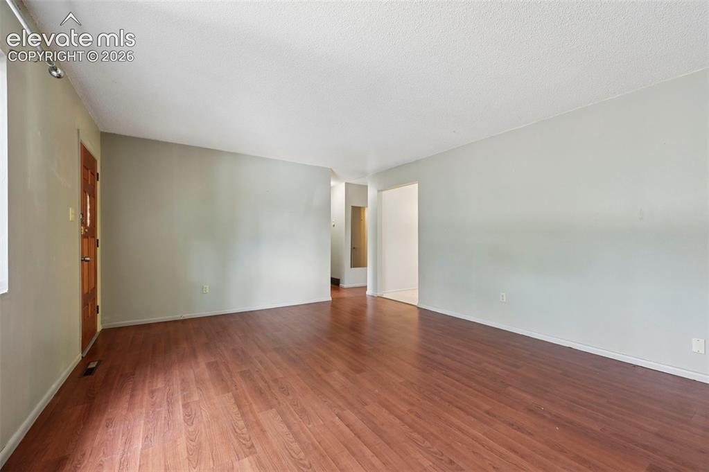 Image 26 of 35: Spacious room featuring wood-finish flooring, light neutral wall paint, and