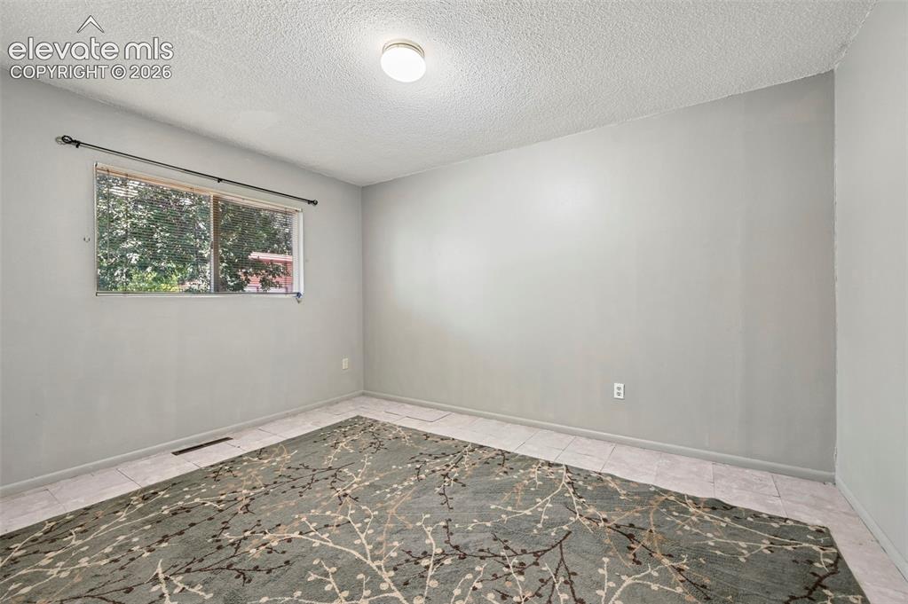 Image 31 of 32: Interior room featuring light gray walls, a single window with a black curt