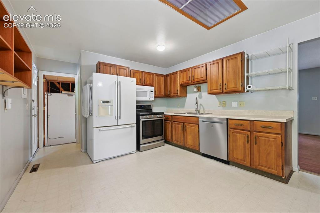 Image 7 of 32: Kitchen featuring wood cabinetry, stainless steel appliances, a white refri