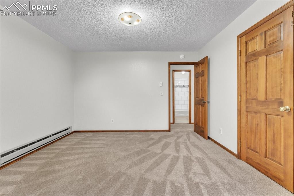 Image 21 of 43: Unfurnished room with light colored carpet, a textured ceiling, and a baseb