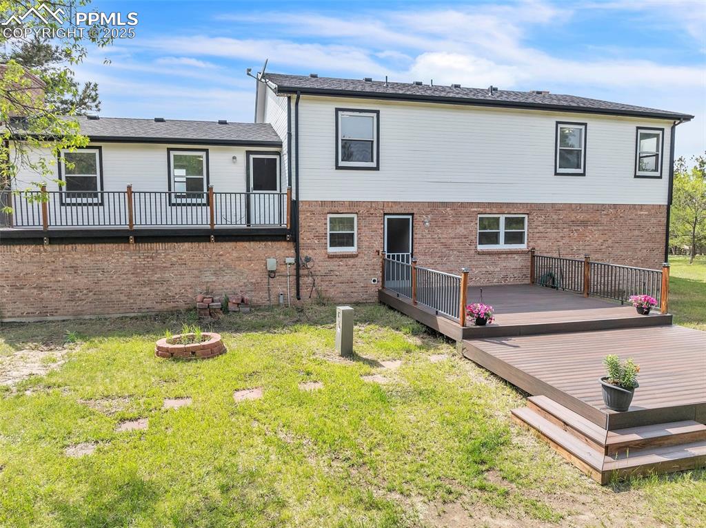 Image 25 of 43: Back of house with a yard, a deck, and brick siding