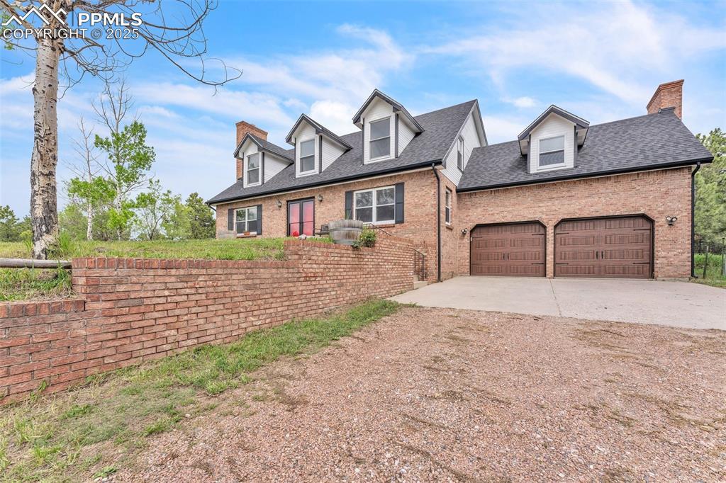 Image 3 of 43: New england style home with concrete driveway, brick siding, a chimney, a s