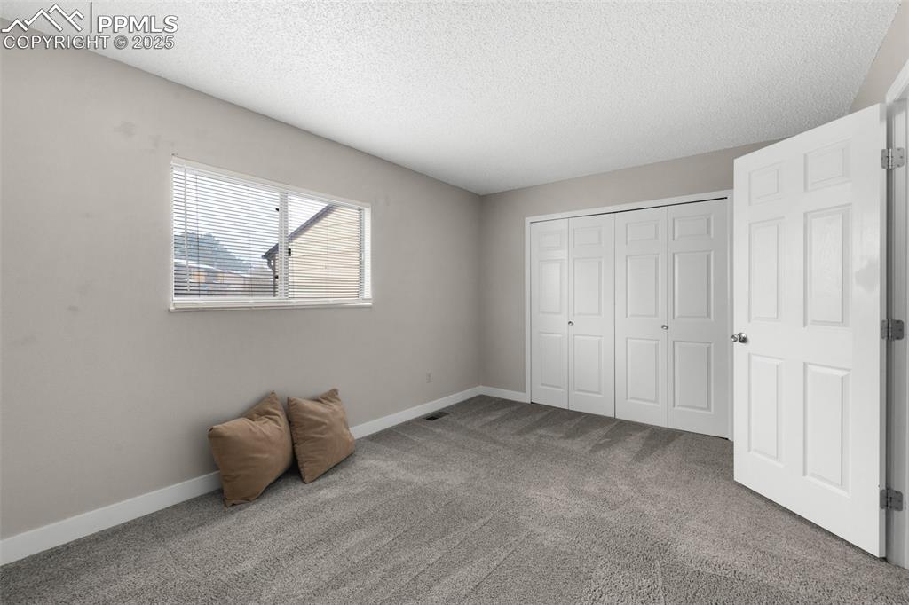 Image 12 of 24: Unfurnished bedroom featuring a closet, carpet flooring, a textured ceiling