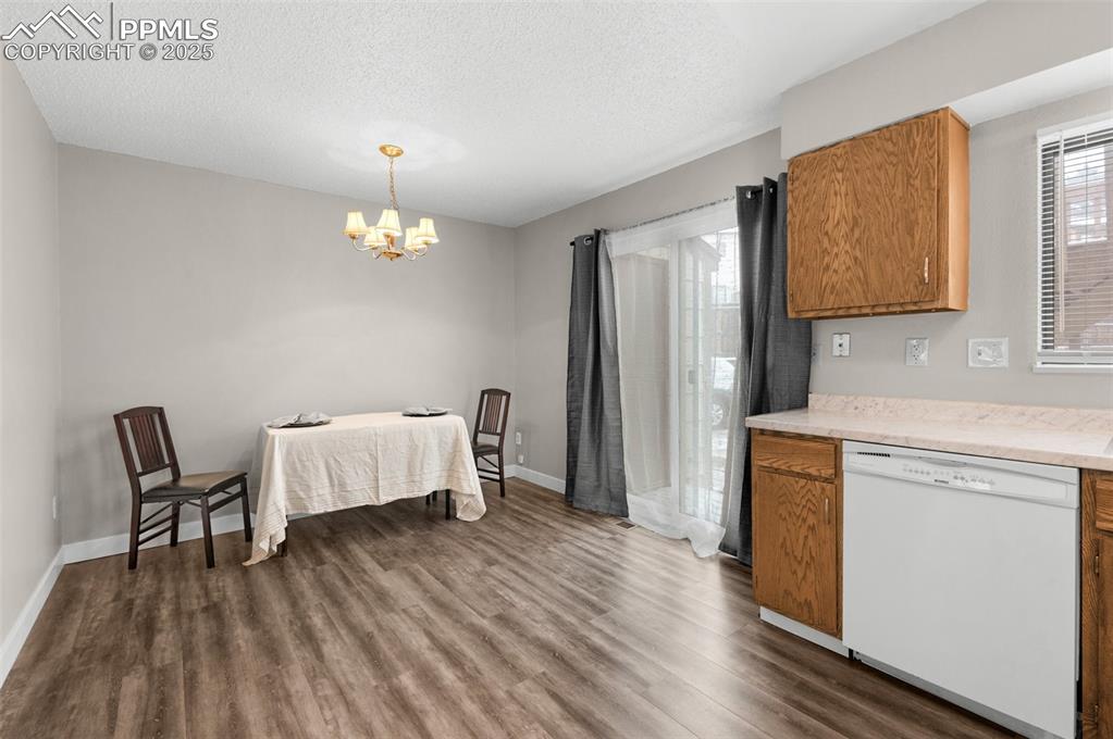 Image 7 of 24: Kitchen with dark wood-type flooring, baseboards, brown cabinets, white dis