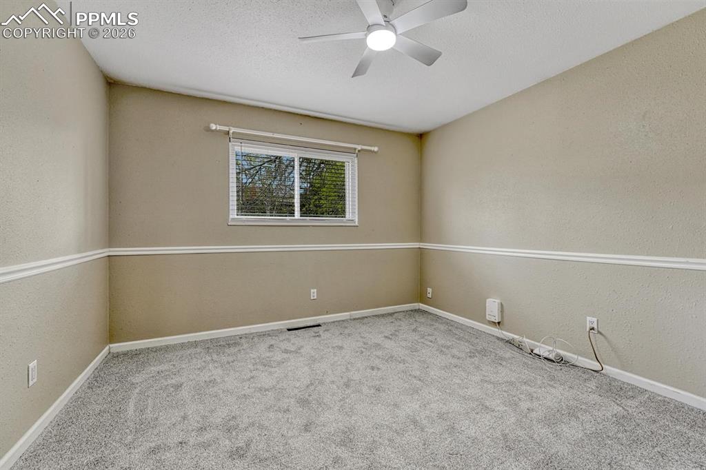 Image 30 of 42: The third upper-level bedroom features plush carpeting and a ceiling fan to