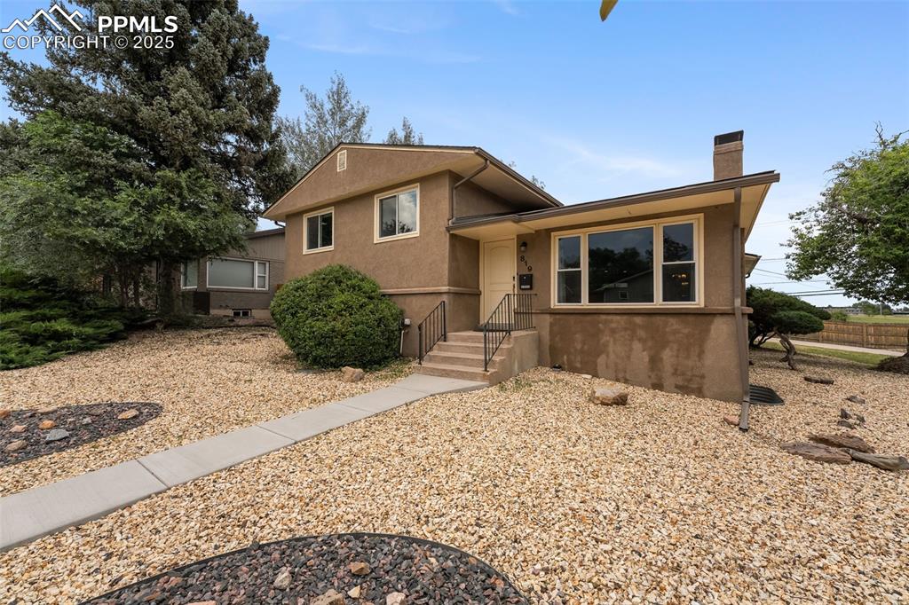 Caption: Split level home with a chimney and stucco siding