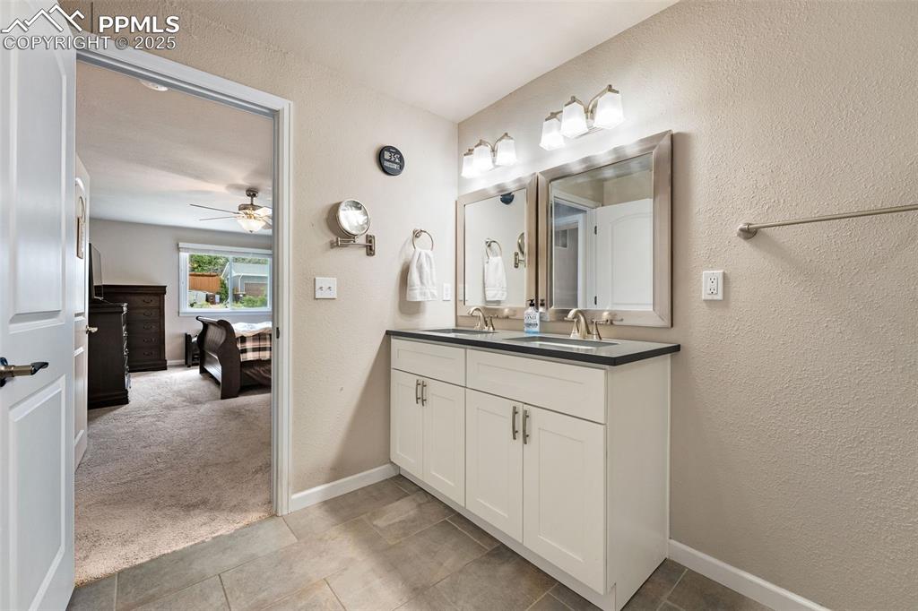 Image 13 of 29: Full bathroom featuring double vanity, a ceiling fan, a textured wall, and