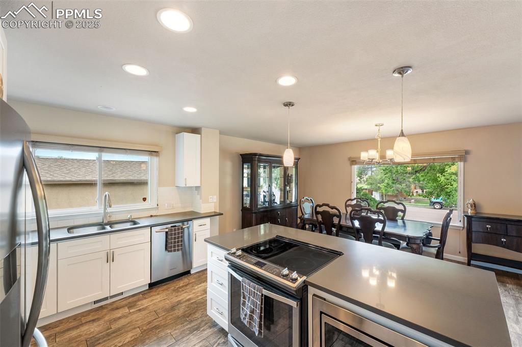 Image 5 of 29: Kitchen with stainless steel appliances, dark countertops, wood finished fl