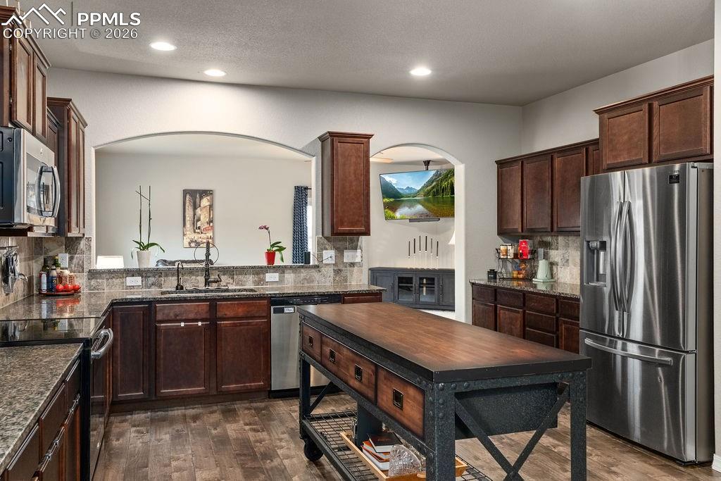 Image 12 of 43: Kitchen with stainless steel appliances, dark wood finish cabinets, dark wo