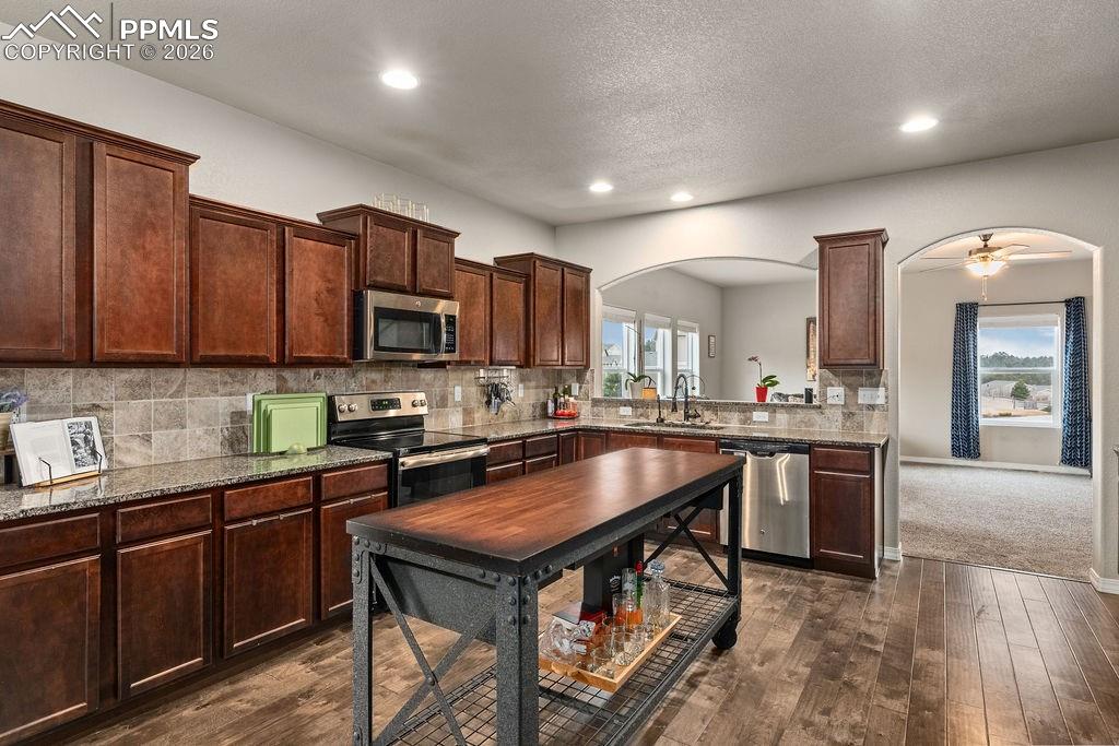 Image 13 of 43: Kitchen with stainless steel appliances, dark wood finish cabinets, dark wo
